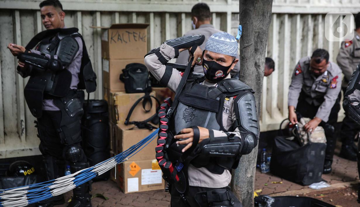 Personel Brimob bersiap mengenakan perlengkapan pelindung diri di Kawasan Bundaran HI, Jakarta, Selasa (13/10/2020). Sebanyak kurang lebih 12 ribu personel gabungan TNI, Polri dan Pemprov DKI Jakarta diterjunkan mengawal aksi tolak Undang-Undang Cipta Kerja Omnibus Law. (Liputan6.com/Faizal Fanani)