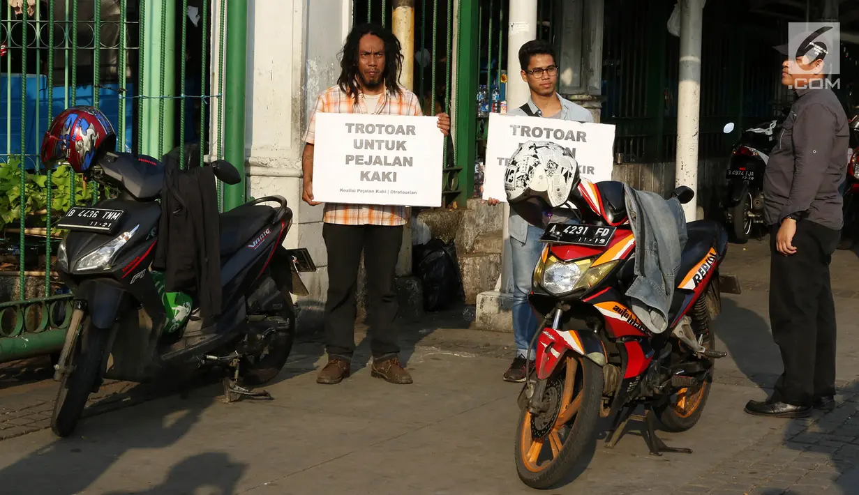 Aktivis Koalisi Pejalan Kaki (KPK) melakukan aksi didekat motor yang terparkir di trotoar kawasan Monas, Jakarta, Jumat (28/7). Aksi tersebut dilakukan untuk mengembalikan fungsi trotoar yang diperuntukkan pejalan kaki. (Liputan6.com/Immanuel Antonius)