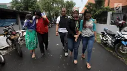 Polisi mengawal tersangka usai menggerebek peredaran narkoba di kawasan Kampung Ambon, Cengkareng, Jakarta Barat, Rabu (24/1). Seorang tersangka berhasil kabur melalui lubang pintu belakang. (Liputan6.com/Arya Manggala)
