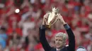 Arsene Wenger memegang trofi hadiah perpisahan di Emirates Stadium, London, (6/5/2018). Arsene Wegner mengumumkan mundur sebagai pelatih setelah 22 tahun bersama Arsenal. (AP/Matt Dunham)