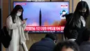 Seorang wanita berjalan di depan layar TV yang menunjukkan gambar file peluncuran rudal Korea Utara saat program berita di Stasiun Kereta Api Seoul, Seoul, Korea Selatan, Selasa (14/3/2023). Korea Utara melakukan uji coba menembakkan dua rudal balistik jarak pendek ke arah perairan timurnya pada hari Selasa dalam unjuk kekuatan kedua Pyongyang minggu ini, sehari setelah dimulainya latihan militer AS-Korea Selatan yang dipandang Korea Utara sebagai latihan invasi. (AP Photo/Ahn Young-joon)