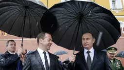 Presiden Rusia Vladimir Putin berbincang dengan PM Rusia Dmitry Medvedev sebelum memimpin upacara kehormatan untuk memperingati invasi Nazi Jerman pada 1941 di Benteng Kremlin di Moskow, Kamis (22/6). (Alexei Druzhinin/Sputnik, Kremlin Pool Photo via AP)