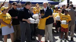 Presiden AS, Donald Trump memeluk seorang anak saat membantu membagikan makanan kepada korban badai Florence di Temple Baptist Church di New Bern, N.C. (19/9). (AP Photo/Evan Vucci)