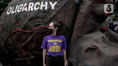 Seorang massa aksi berdiri dekat replika gurita raksasa oligarki saat aksi di Patung Kuda, Jakarta, Selasa (8/3/2022). Aksi tersebut untuk memperingati Hari Perempuan Internasional serta menuntut pengesahan RUU TPKS yang partisipatif dalam pembahasan dan pro korban. (Liputan6.com/Faizal Fanani)