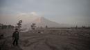 Seorang pria berdiri di depan Gunung Semeru menyusul letusan gunung berapi di desa Kajar Kuning di Lumajang (5/12/2022). Gunung Semeru meletus pada tanggal 4 Desember memuntahkan awan abu panas setinggi satu mil dan sungai lava di sisinya sambil memicu evakuasi hampir 2.000 orang tepat satu tahun setelah letusan besar terakhirnya menewaskan puluhan orang. (AFP/Juni Kriswanto)