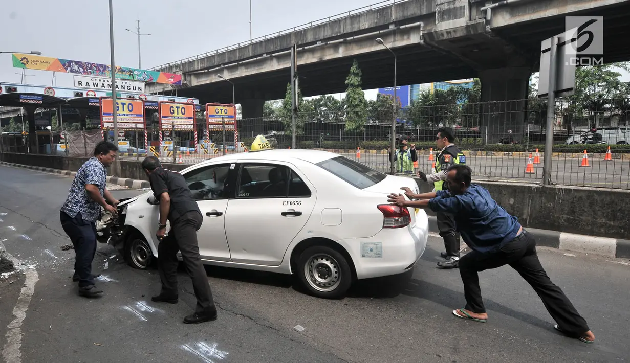 Warga mendorong mobil taksi yang menabrak tiang di Jalan Ahmad Yani, Jakarta, Rabu (1/8). (Merdeka.com/Iqbal Nugroho)