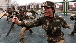 Tentara wanita China berlatih menggunakan pisau saat latihan militer jelang Hari Perempuan Internasional di Hefei, China (6/4). (AFP)