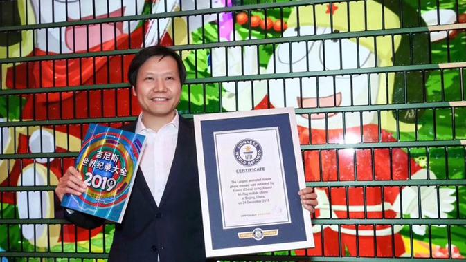 CEO Xiaomi Lei Jun memegang sertifikat rekor dunia di hadapan pohon Natal dari ribuan Xiaomi Mi Play (Foto: techgenyz)