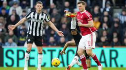 Pemain Nottingham Forest, Chris Wood, berebut bola dengan pemain Newcastle United, Joelinton, dalam lanjutan Liga Inggris di St James Park, Selasa (26/12/2023). Apesnya lagi aktor kekalahan The Magpies adalah mantan pemainnya sendiri yakni Chris Wood. (AFP/Andu Buchanan)