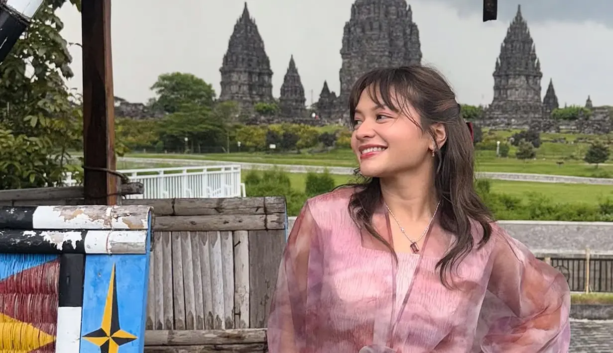 Amel Carla tampil anggun dalam balutan kebaya modern berwarna pastel. Latar belakang Candi Prambanan menambah kesan dramatis pada foto tersebut. Rambutnya dibiarkan terurai dengan gaya wavy natural, dipadukan dengan riasan natural. (Liputan6.com/IG/@amelcarla)