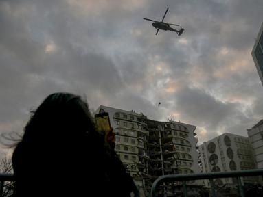 Seorang anggota pasukan khusus mencoba mendaratkan helikopter di sebuah bangunan rusak yang diperkirakan berisi beberapa hewan di Diyarbakir, Turki tenggara (22/2/2023). Para pecinta hewan di kota Turki yang porak-poranda akibat gempa mematikan memprotes pada 22 Februari 2023, setelah pejabat berusaha menghancurkan bangunan rusak yang diduga berisi beberapa hewan, koresponden AFP melihat. (AFP/Ilyas Akengin)