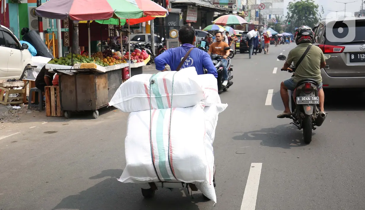 Seorang porter membawa pakaian jadi yang di kemas di karung di Kawasan Tanah Abang, Jakarta, Senin (11/10/2021). Menurunnya level PPKM jakarta menjadi level 3 membawa berkah bagi para kuli panggung dikarenakan geliat pasar tersebut kembali berjalan. (Liputan6.com/Angga Yuniar)