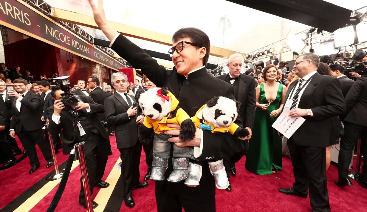 Ada yang menarik perhatian dalam acara Oscar tersebut. Aktor laga, Jackie Chan hadir dengan membawa dua boneka panda. Sontak, kehadirannya menarik perhatian para awak media dan tamu undangan lain. (AFP/Bintang.com)