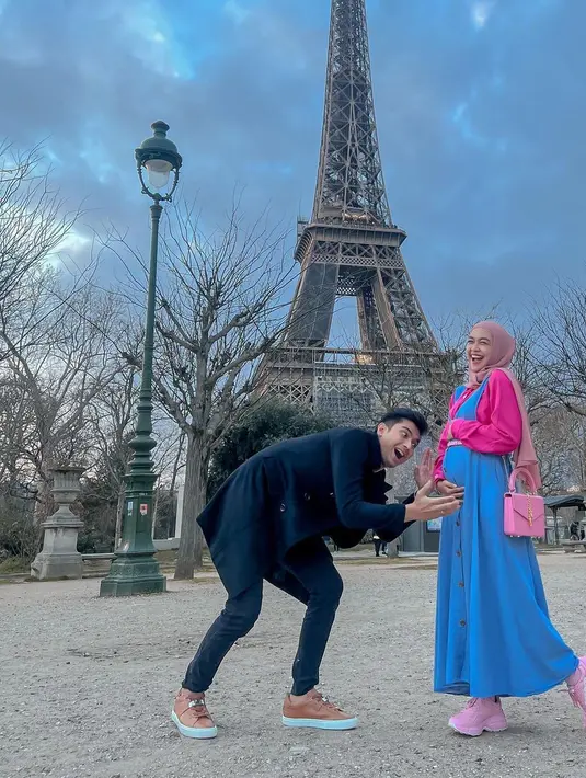 Dress Overall jeans dan kemeja shocking pink untuk gaya cute di Paris. Dilengkapi dengan sneaker dan tas berwarna senada. (Foto: Instagram @riaricis1795)