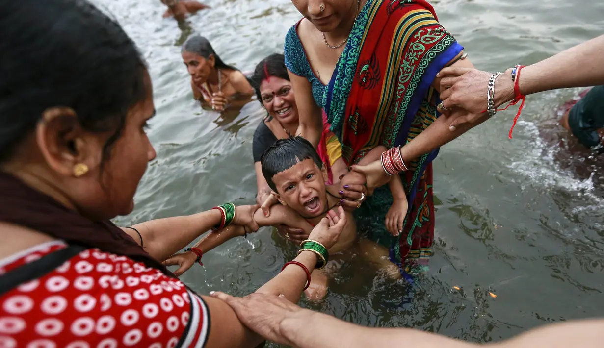 Seorang anak menangis saat dimandikan di Sungai Godavari saat Festival Pitcher, India, Jumat (28/8/2015). Ratusan ribu umat Hindu mengambil bagian dalam perayaan keagamaan yang diadakan setiap 12 tahun sekali di Sungai Godavari. (REUTERS/Danish Siddiqui)
