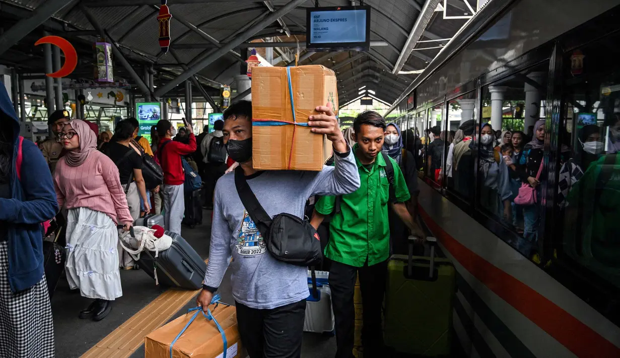 Calon penumpang Kereta Api Jarak Jauh (KAJJ) bersiap menaiki rangkaian kereta di stasiun Gubeng, Surabaya, 28 Maret 2025. (JUNI KRISWANTO/AFP)