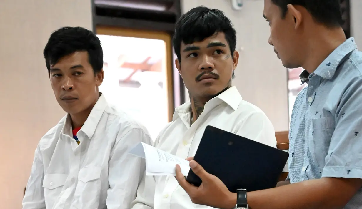 Warga negara Thailand, Prakob Seetasang (kiri) dan Adison Phonlamat (tengah) saat menjalani persidangan kasus penyelundupan narkoba di pengadilan Denpasar, Bali (23/9/2019). Jaksa menuntut 2 pria Thailand tersebut dengan hukuman penjara 18 tahun. (AFP Photo/Sonny Tumbelaka)