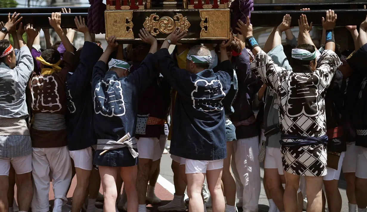 Sejumlah peserta mengenakan pakaian tradisional Happi mengangkat Mikoshi saat festival Tenno-sai di Kuil Susanoo di Tokyo, Jepang (3/6). Tenno-sai adalah perayaan Jepang dalam agama Shinto untuk menghormati kaisar masa lalu. (AP Photo / Eugene Hoshiko)
