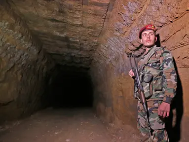 Tentara Suriah berjaga di terowongan yang sebelumnya digunakan oleh pemberontak di Jobar, Ghouta Timur, Senin, (2/4). Terowongan itu digunakan untuk menyelundupkan barang-barang dan berlindung. (LOUAI BESHARA/AFP)