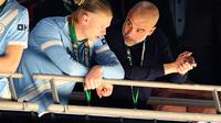 Momen Pep Guardiola (kanan) berbincang dengan Erling Haaland usai menerima medali juara Carabao Cup. Pada partai final, Man City mengalahkan Arsenal 2-0. (Adrian Dennis / AFP)