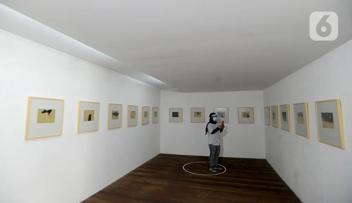 Pengunjung berjaga jarak fisik saat melihat pameran karya pelukis Hanafi berjudul 60 tahun dalam studio di Galerikertas, Depok, Jawa Barat, Selasa (7/7/2020).  Pameran tersebut menerapkan protokol kesehatan guna mencegah penyebaran COVID-19. (merdeka.com/Arie Basuki)