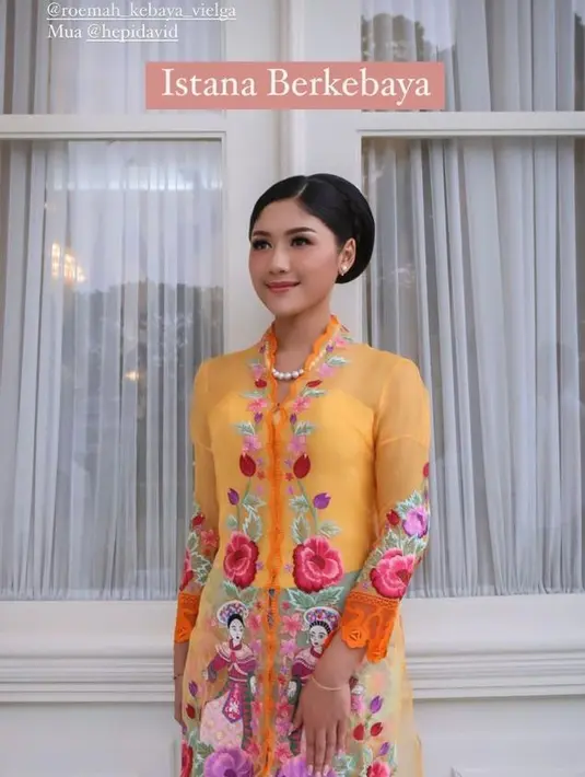 Kebaya encim oranye ini terlihat makin mencolok dengan batik Betawi blue sky yang dikenakannya. Rambut Erina pun hanya disanggul rapi,  dipermanis dengan kalung dan anting mutiara. [Instagram/erinagudono]
