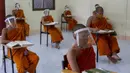 Para biksu muda mengenakan masker dan pelindung wajah saat belajar agama di Molilokayaram Educational Institute, Bangkok, Thailand, Rabu (15/4/2020). Sekitar 200 biksu muda tetap bersekolah kendati Thailand menutup semua sekolah selama lockdown akibat COVID-19. (AP Photo/Gemunu Amarasinghe)