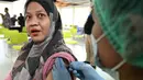 Para pekerja bandara I Gusti Ngurah Rai Bali menerima vaksin penguat virus corona Covid-19 Inavac. (SONNY TUMBELAKA/AFP)