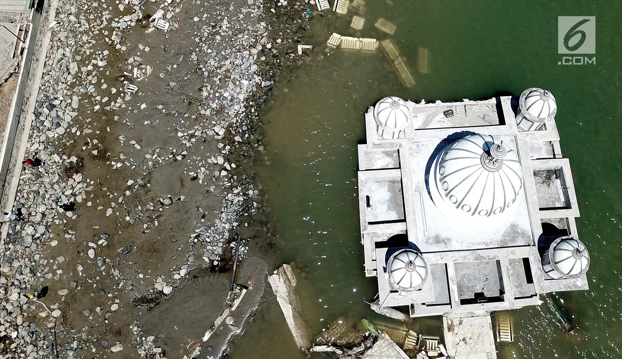 Pandangan udara Masjid Terapung Arqam Bab Al Rahman pasca gempa dan tsunami Palu di Pantai Talise, Sulawesi Tengah. Bangunan masjid yang terletak di pinggir pantai terlihat utuh meski sebagian bangunannya tenggelam. (Liputan6.com/Fery Padolo)