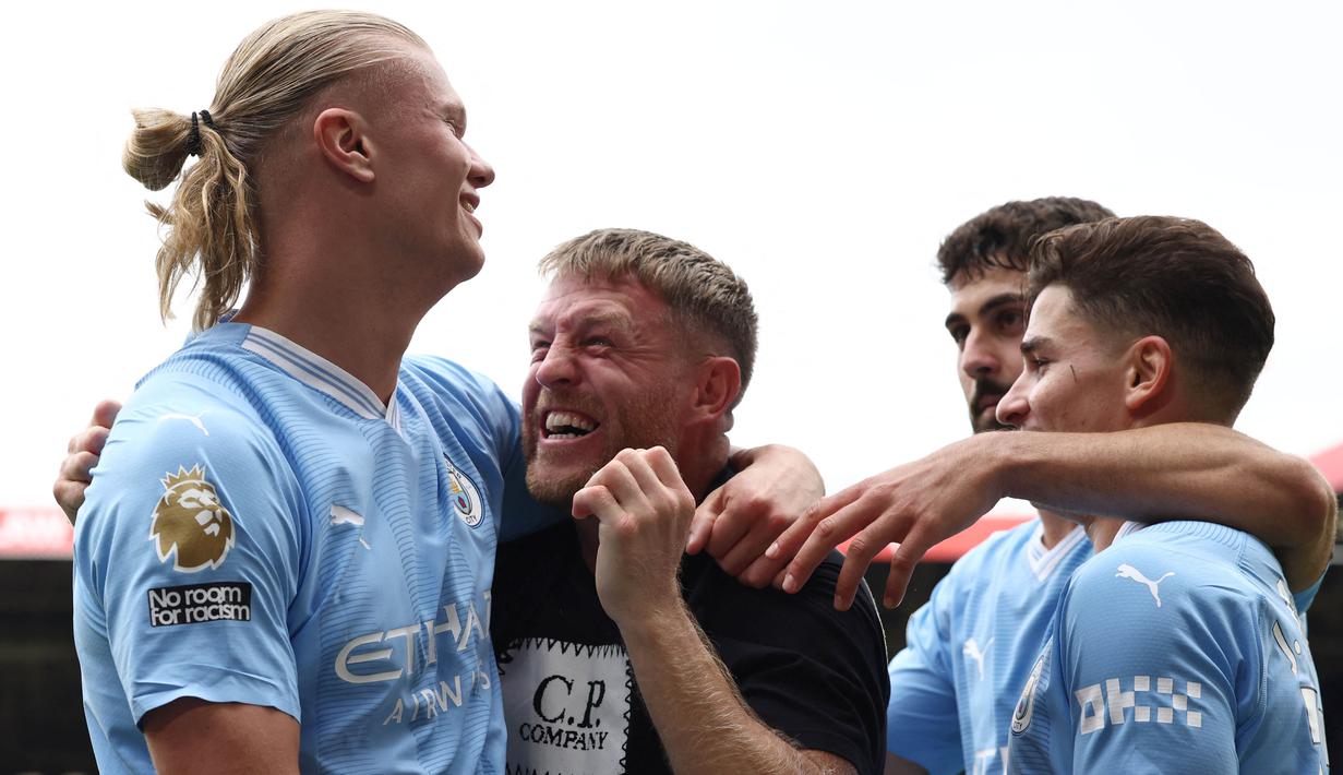 Erling Haaland pun sempat memeluk pitch invader yang bernama Terry Flanagan. Terry bukan merupakan sembarang fans. Ia merupakan seorang mantan petinju kelahiran Manchester dan pernah menjadi juara dunia. (AFP/Darren Staples)