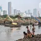 Anak-anak bermain dekat alat berat yang tengah mengerjakan pengerukan lumpur di Kali Ciliwung Segmen Kanal Banjir Barat (KBB), Tanah Abang, Kamis (30/9/2021). Gerebek Lumpur dilakukan secara serentak di lima wilayah Ibu Kota. (merdeka.com/Iqbal S. Nugroho)