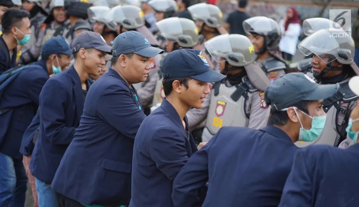 Massa dari Badan Eksekutif Mahasiswa Seluruh Indonesia (BEM SI) bersalaman dengan polisi saat aksi unjuk rasa di sekitar DPR RI, Jakarta, Selasa (1/10/2019). Selain berorasi secara damai, para mahasiswa membagikan bunga untuk para polisi yang mengawal aksi mereka. (Liputan6.com/Immanuel Antonius)