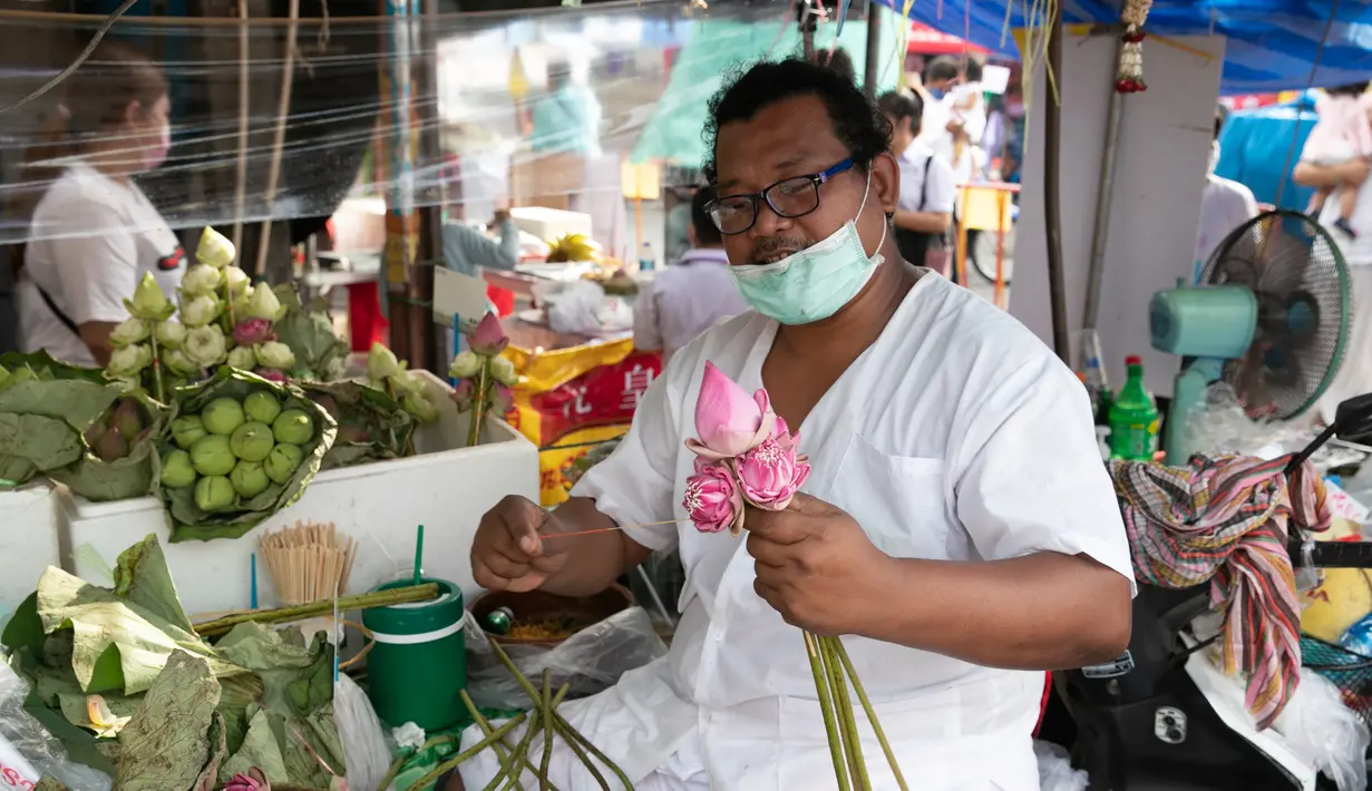 Seorang pedagang menjual bunga lotus dalam Festival Vegetarian Phuket 2020 di Phuket, Thailand (20/10/2020). Festival ini tetap menjalankan kebijakan jaga jarak sosial (social distancing) ketat di tengah pandemi COVID-19 yang masih berlangsung. (Xinhua/Zhang Keren)