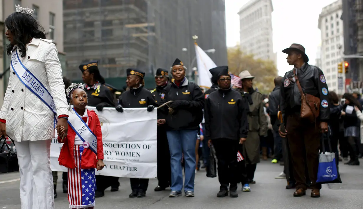 Seorang gadis berdiri dengan veteran militer AS dalam parade perayaan Hari Veteran di New York, Amerika Serikat, Rabu (11/11). Hari Veteran adalah hari libur nasional untuk menghormati jasa para tentara Amerika. (REUTERS/Shannon Stapleton)