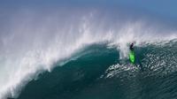 Peselancar Evan Valiere menjelajah ombak besar di Pantai Utara O’ahu, Hawaii, Senin (26/11). (Brian Bielmann / AFP)