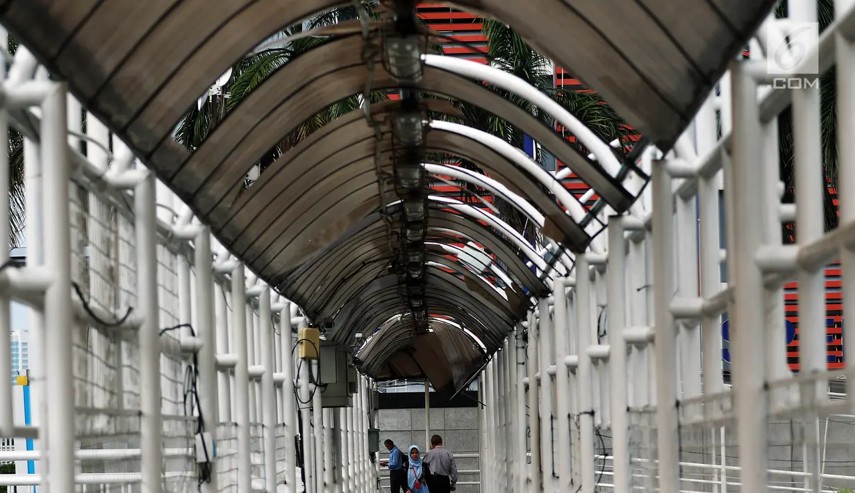 Warga melintasi Jembatan Penyeberangan Orang (JPO) yang rusak di kawasan Dukuh Atas, Jakarta, Rabu (12/12). Rusaknya JPO Dukuh Atas menggangu pejalan kaki yang melintas. (Liputan6.com/JohanTallo)