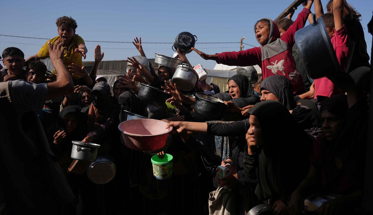 Warga Palestina menunggu bantuan gula dan beras di dapur umum di Khan Younis, Jalur Gaza selatan, Jumat, 31 Oktober 2025. Namun, sering kali, makanan yang tersedia seperti sup, nasi, atau lentil rebus, sangat terbatas dan banyak yang pulang dengan tangan kosong karena kehabisan. (AP Photo/Abdel Kareem Hana)