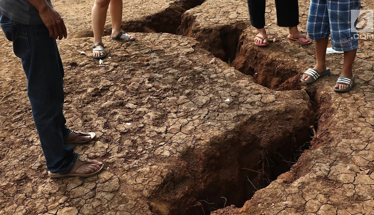 Warga mengamati tanah terbelah di lapangan RT 02 RW 02 Kampung Pedurenan, Kelurahan Cisalak Pasar, Cimanggis, Depok, Jabar, Senin (22/10). Penyelidikan tanah terbelah untuk mengetahui penyebab dan penanganan lanjutannya. (Liputan6.com/Immanuel Antonius)