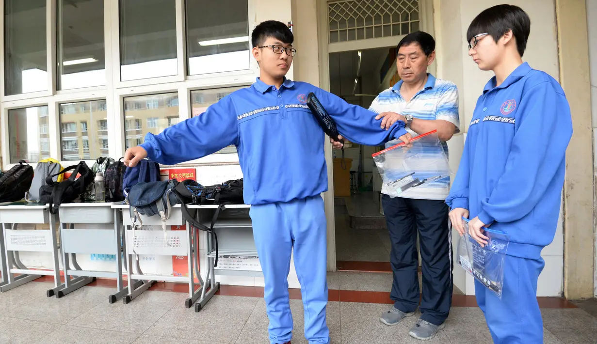 Pengawas mengidentifikasi peserta ujian masuk perguruan tinggi di Handan, Provinsi Hebei, China, (6/6). Pemeriksaan menggunakan metal detector hingga pendeteksi sidik jari dan wajah. (AFP/STR)