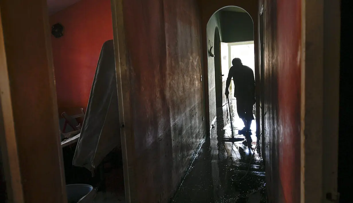 Carlos Gelez memindahkan air banjir dari dalam rumahnya di Mata Redonda, Maracay, Venezuela, Rabu (21/10/2020). Lusinan keluarga mencari perlindungan di atap rumah mereka untuk melindungi barang pribadi mereka. (AP Photo/Matias Delacroix)