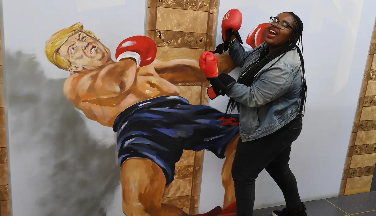 Seorang wanita mengenakan sarung tinju berpose di depan gambar 3 dimensi Presiden AS Donald Trump di Museum of Illusions, Hollywood, California (27/3). Di pameran ini pengunjung bisa berfoto dengan gaya yang unik dan terihat nyata.(AFP Photo/Mark Ralston)
