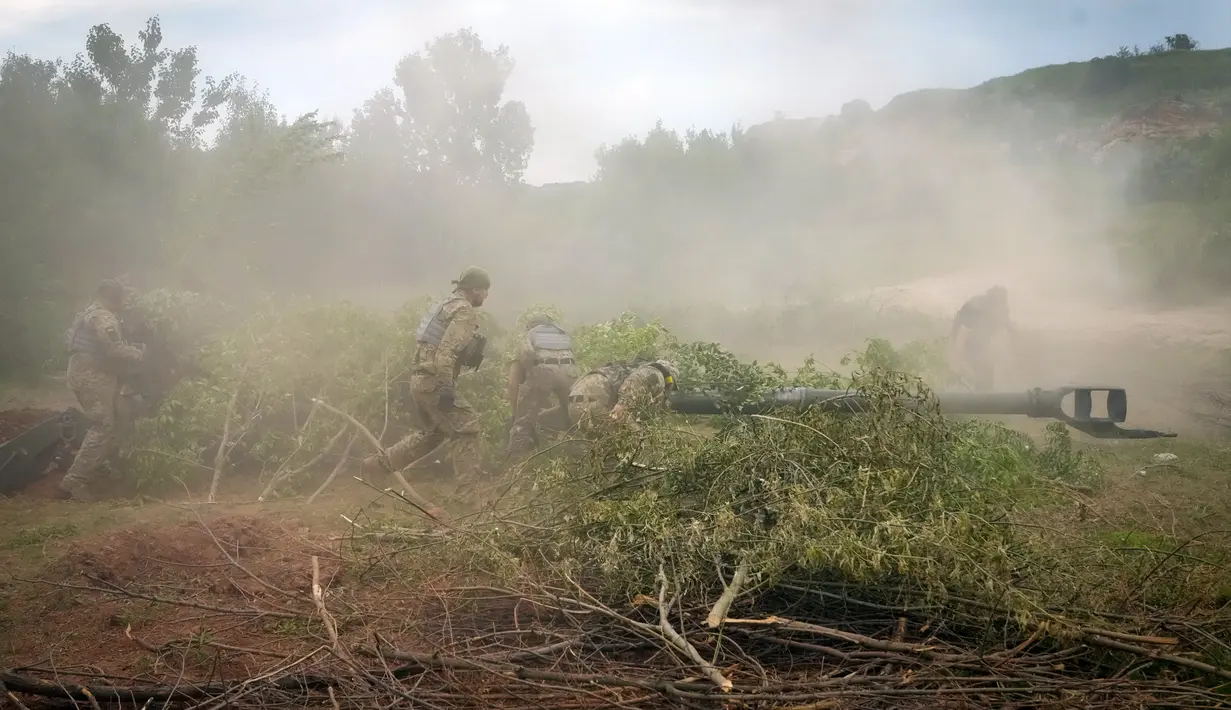 Tentara Ukraina menyamarkan howitzer M777 yang dipasok Amerika Serikat (AS) dengan cabang-cabang pohon setelah mereka menembaki posisi Rusia di wilayah Donetsk, Ukraina, 18 Juni 2022. (AP Photo/Efrem Lukatsky)