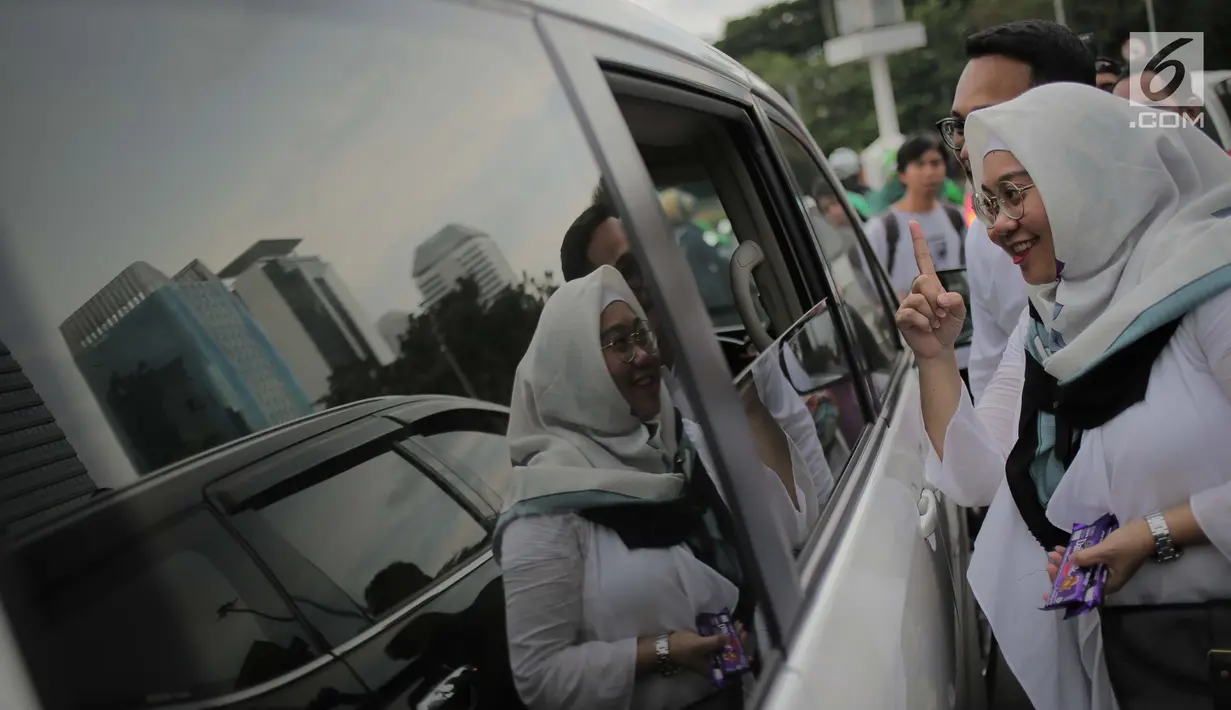 Relawan Millennial Jokowi-Amin membagikan coklat kepada pengendara roda dua dan empat di kawasan Patung Kuda, Jakarta, Kamis (18/4). Kegiatan tersebut sebagai bentuk terima kasih kepada seluruh anak bangsa yang telah ikut memberikan suaranya di TPS. (Liputan6.com/Faizal Fanani)