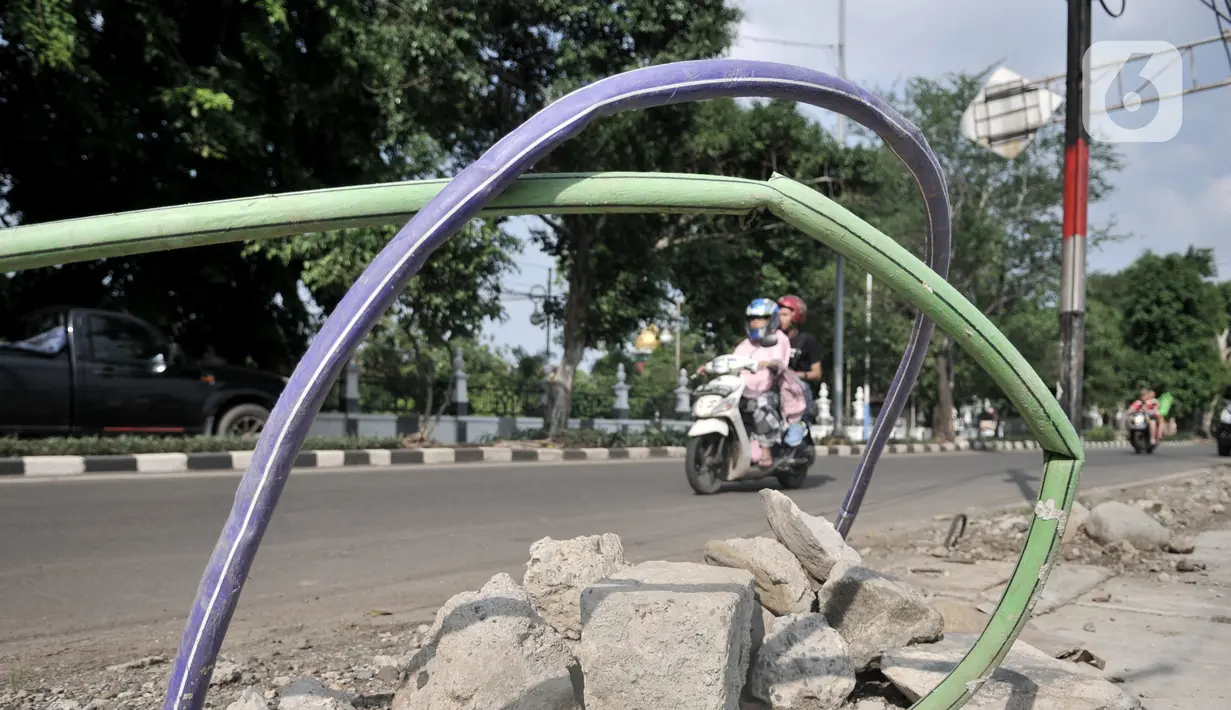 Kendaraan melintasi kabel proyek PLN yang terbengkalai di Jalan Jatinegara Kaum, Jakarta, Minggu (12/1/2020). Kurangnya pengawasan dalam penyelesaian proyek instalasi listrik bawah tanah PLN tersebut menyebabkan banyak kabel masih muncul di trotoar dan bahu jalan. (merdeka.com/Iqbal S. Nugroho)
