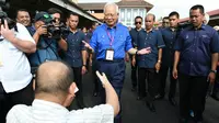Perdana Menteri Malaysia, Najib Razak menyapa seorang pendukung di tempat pemungutan suara selama pemilihan umum di Pekan, Rabu (9/5). Pemilu ini pertarungan antara PM Najib yang sudah berkuasa sejak 2009, melawan Mahathir Mohamad. (MOHD RASFAN / AFP)