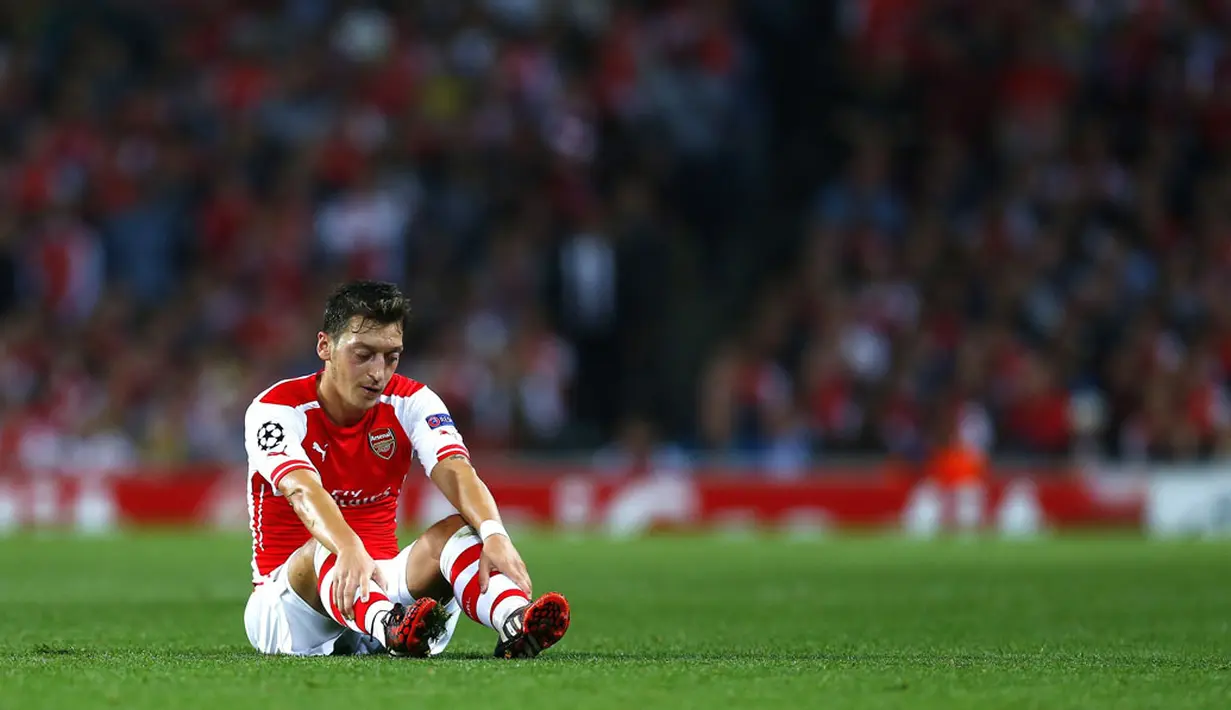 Gelandang Arsenal, Mesut Ozil, terduduk usai gagal memanfaatkan peluang mencetak gol ke gawang Besiktas di ajang play-off Liga Champions di Stadion Emirates, London, (28/8/2014). (REUTERS/Eddie Keogh)