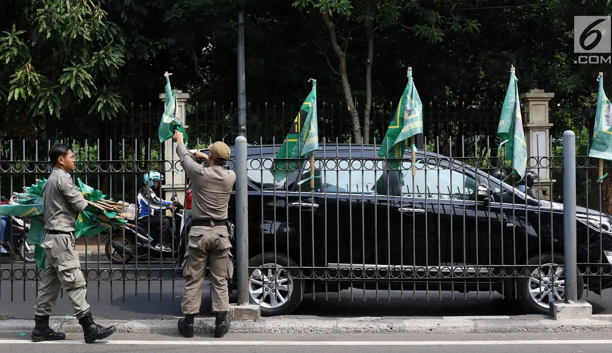 Petugas Satpol PP mencopot bendera partai politik di sepanjang pagar kawasan Pancoran, Jakarta. Selasa (18/7). Pencopotan dilakukan untuk menertibkan bendera partai politik liar yang memenuhi ruang publik di Ibukota. (Liputan6.com/Immanuel Antonius)