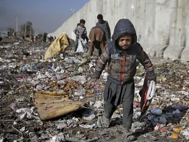 Seorang anak Afghanistan yang kehilangan tempat tinggalnya mencari barang-barang plastik dan lainnya yang dapat digunakan sebagai pengganti kayu bakar, di tempat pembuangan sampah di Kabul, Afghanistan (15/12/2019). (AP Photo/Altaf Qadri)