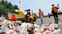 Petugas kebersihan dari dinas kebersihan Pemprov DKI Jakarta bekerja ekstra untuk membersihkan sampah di  kawasan Monumen Nasional, Jakarta, (31/7/2014). (Liputan6.com/Faizal Fanani)