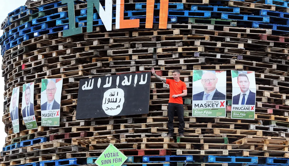 Poster para politisi Sinn Fein dipajang di tumpukan palet kayu yang akan digunakan membuat api unggun di Ballymacash, Lisburn, Irlandia Utara (10/7). (AFP Photo/Paul Faith)